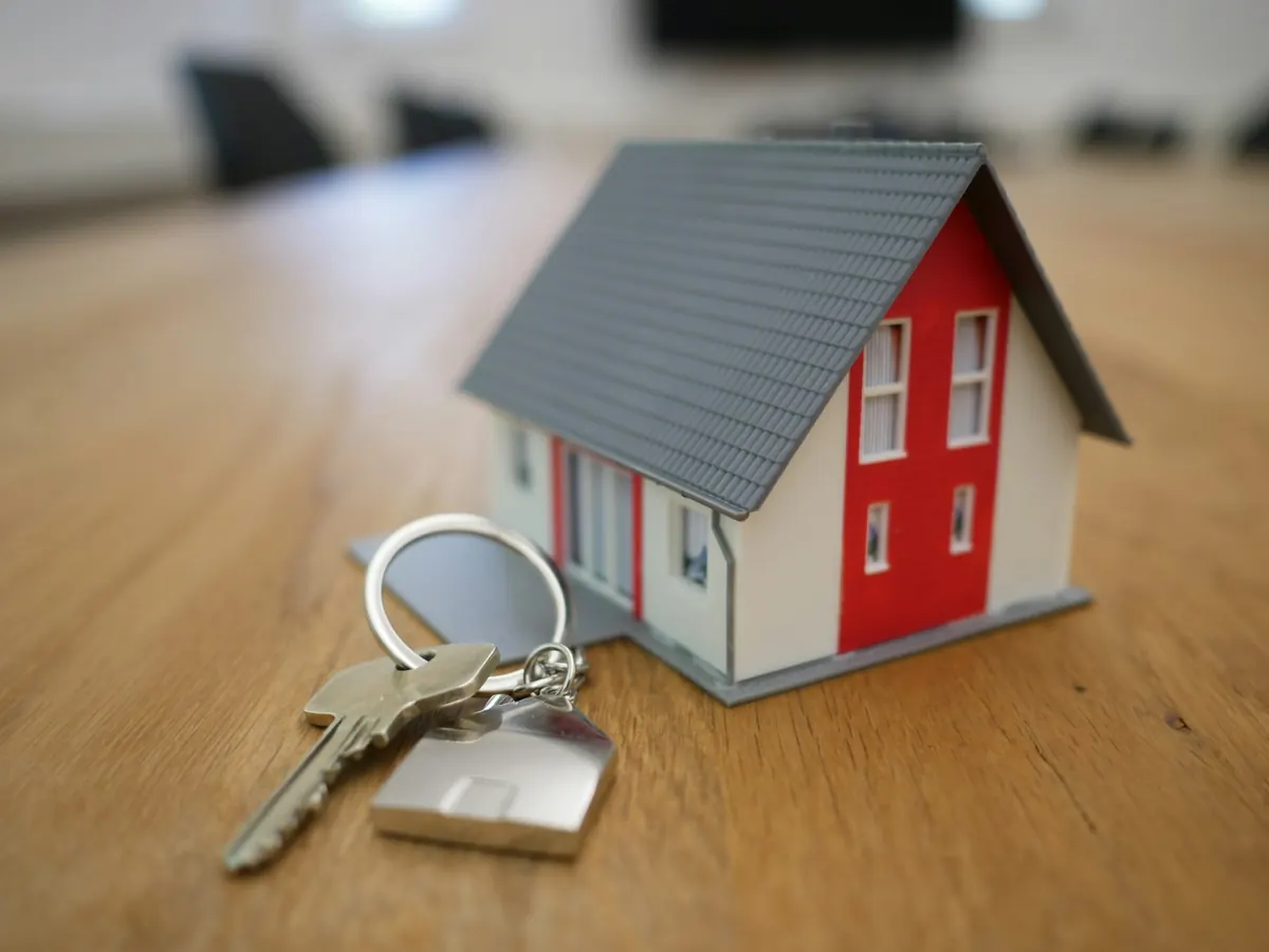 Chaveiro de casinha ao lado de uma miniatura de casa