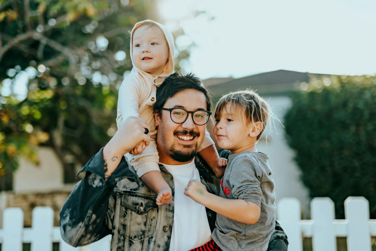 Pai carregando o filho nas costas em frente à casa da família